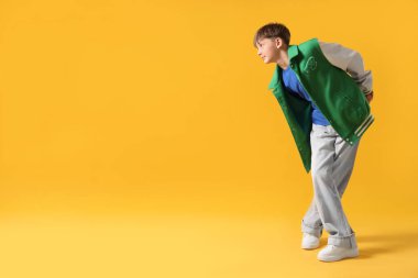 Şık giyinmiş çocuk turuncu arka planda dans ediyor, mesaj için yer var.