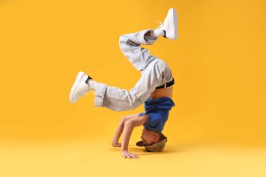 Şık giyinmiş çocuk turuncu arka planda dans ediyor.