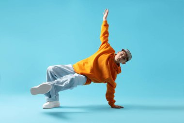 Şık giyinmiş çocuk açık mavi arka planda dans ediyor.