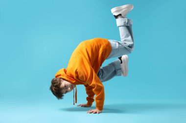 Şık giyinmiş çocuk açık mavi arka planda dans ediyor.