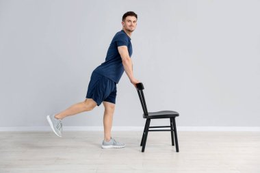 Evde sandalyeyle egzersiz yapan yakışıklı adam.