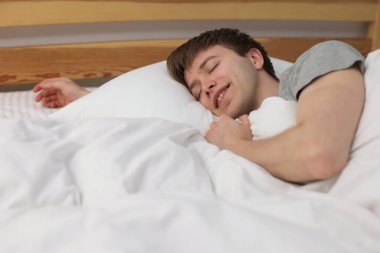 Evde yatakta uyuyan gülümseyen adam