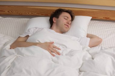 Genç adam yatağında uyuyor.