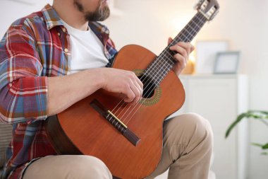Evde akustik gitar çalan adam, yakın plan.