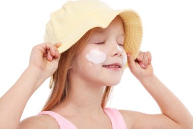 Yanaklarında güneş kremiyle gülümseyen küçük kız beyaz arka planda, yakın plan