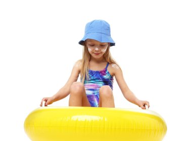 Cildinde güneş kremi ve beyaz arka planda şişme yüzük olan sevimli küçük bir kız.