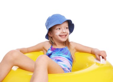 Cildinde güneş kremi ve beyaz arka planda şişme yüzük olan gülümseyen küçük bir kız.