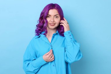Açık mavi arka planda parlak mor saçlı güzel bir kadın.
