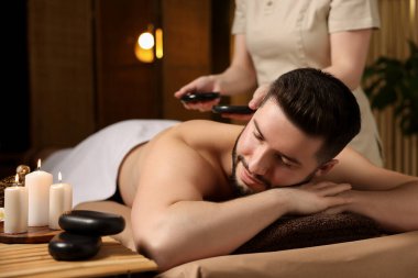 Adam spa salonunda taşlarla masaj yaptırıyor.