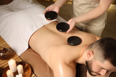 Adam spa salonunda taşlarla masaj yaptırıyor.