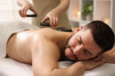 Adam spa salonunda taşlarla masaj yaptırıyor.