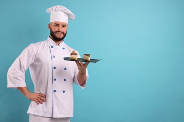 Üniformalı mutlu pastacı açık mavi arka planda lezzetli cheesecake parçaları tutuyor, mesaj için yer var.