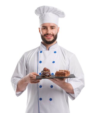Üniformalı mutlu pastacı beyaz arka planda lezzetli çikolatalı tatlılar tutuyor.