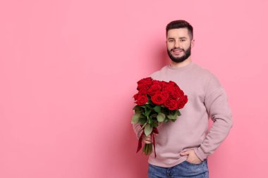 Pembe arka planda kırmızı gül buketi olan mutlu adam, mesaj için yer.