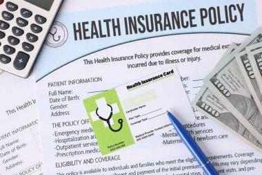 Sağlık sigortası kartı, poliçe, para, hesap makinesi ve kalem, yakın plan.