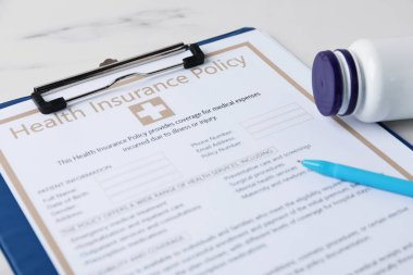 Sağlık sigortası poliçesi, kalem ve tıbbi şişe beyaz mermer masa, yakın plan.