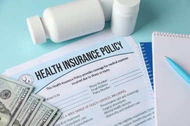 Sağlık sigortası poliçesi, para ve turkuaz arka planda tıbbi şişeler.