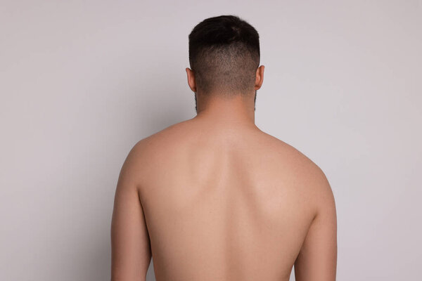Man before scoliosis treatment on light background, back view