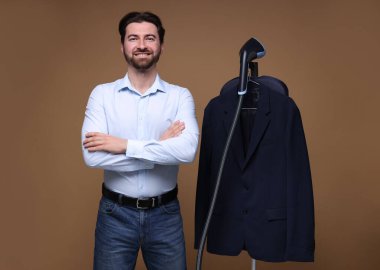 Kahverengi arka planda vapuru ve ceketi olan adam.