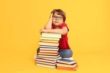 Turuncu arka plan hakkında çok farklı kitapları olan bir çocuk.