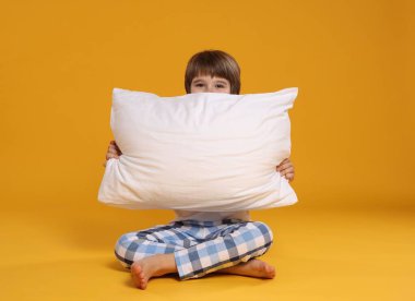 Turuncu arka planda yastığı olan tatlı bir çocuk.