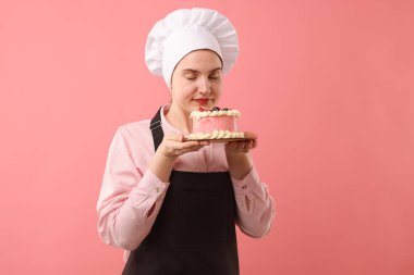 Şekerci pembe arka planda lezzetli bir pasta tutuyor.