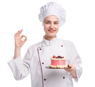 Üniformalı mutlu pastacı elinde böğürtlenli lezzetli bir pasta tutuyor ve beyaz arka planda güzel bir jest yapıyor.