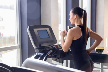 Spor salonunda koşu bandında antrenman yapan atletik kadın.
