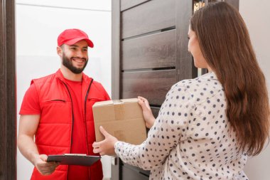 Elinde dosya olan gülen kurye içerideki alıcıya paket veriyor.