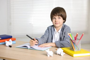 Evde, masada ödev yapan sevimli küçük çocuk.