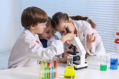 Çocuklar içeride masada kimyasal deneyler yapıyorlar.