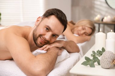 Spa salonundaki masaj masalarında uzanan mutlu çift, seçici odak