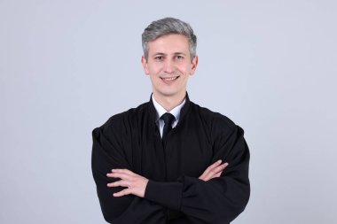 Gri arka planda çapraz kollu gülümseyen yargıç