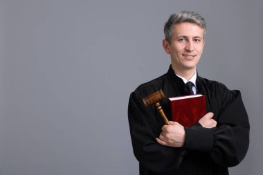 Çekiç ve gri arka plan kitabı ile gülümseyen yargıç. Metin için boşluk