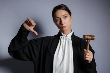 Aydınlık arkaplanda başparmak gösteren çekiçli yargıç