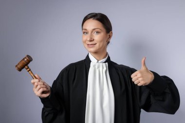 Aydınlık arkaplanda başparmak gösteren çekiçli yargıç