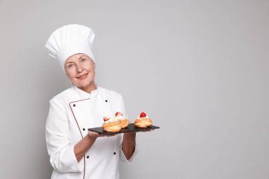 Açık gri arka planda Choux 'lu profesyonel pasta şefi. Metin için boşluk