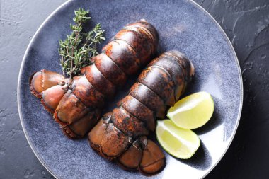 Çiğ ıstakoz kuyruğu, kireç ve kekik siyah masada, üst manzara