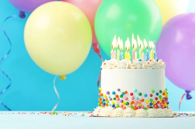 Renkli süslemeli nefis bento keki ve mavi arka planda yanan mumlar. Metin için boşluk