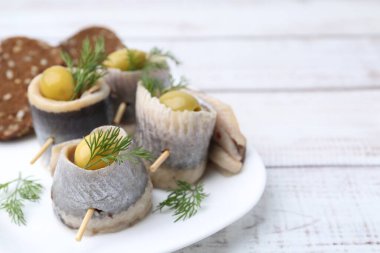 Zeytinli lezzetli ringa dürümleri, beyaz ahşap masada dereotu ve ekmek, yakın plan. Metin için boşluk