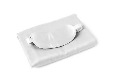 Beyaz arka planda ipek çarşaflar ve uyku maskesi.