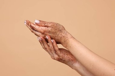 Bej arka planda ellerini ovuşturan kadın, yakın plan.