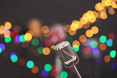 Karanlık arka planda bulanık ışıkları olan klasik mikrofon, mesaj için yer. Müzik ekipmanları