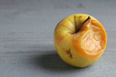 Gri ahşap masada çürük bir elma, yakın plan. Metin için boşluk