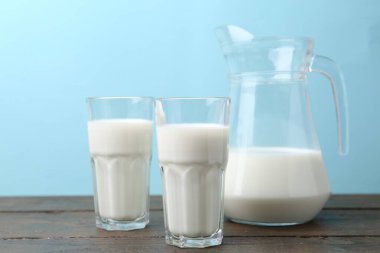 Tahta masada açık mavi arka plana karşı taze süt.