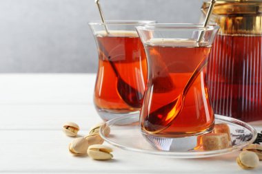 Lezzetli Türk çayı, şeker ve şam fıstığı beyaz ahşap masada, yakın plan.