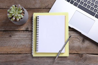 Boş defterler, dizüstü bilgisayarlar, ev bitkisi ve kalem ahşap masa, düz uzanma