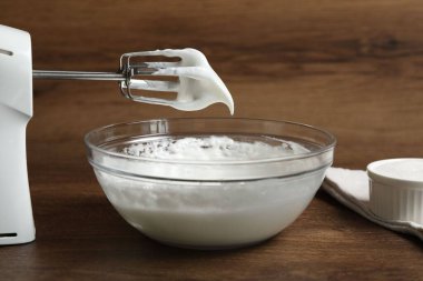 Çırpılmış çırpılmış çırpılmış krema ve çırpılmış krema ile ahşap masada, yakın plan.