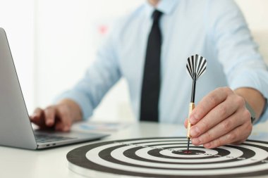 Dart oklu bir adam içeride çalışırken dart tahtasına nişan alıyor, yakın plan.