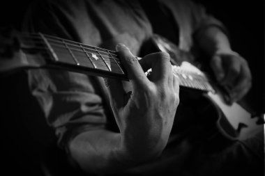 Karanlıkta gitar çalan adam, yakın plan. Siyah ve beyaz etkisi